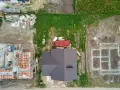 Widok z lotu ptaka na plac budowy z fundamentami, częściowo zbudowanym domem i materiałami budowlanymi.