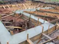 Budowa fundamentów: świeży beton i drewniane szalunki pokazują, jak połączyć stary fundament z nowym.