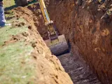Koparka pogłębia wykop pod garaż. Widać jaki głęboki fundament pod garaż powstaje.
