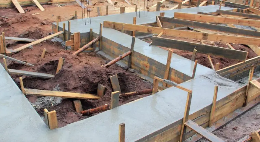 Budowa fundamentów: świeży beton i drewniane szalunki pokazują, jak połączyć stary fundament z nowym.